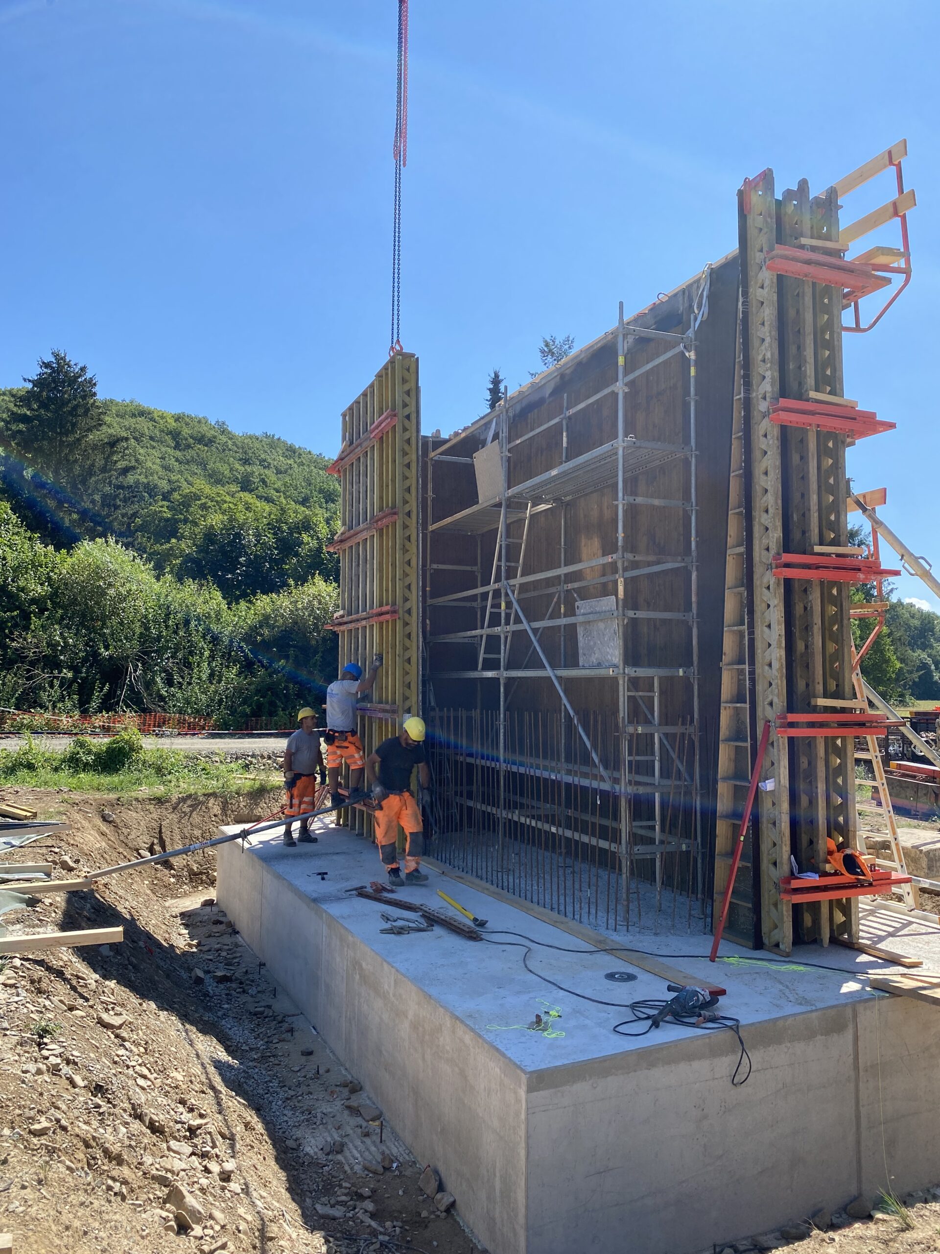 Infrastrukturbaustelle mit massiver Schalung, Kran und Ausfuehrungspersonal